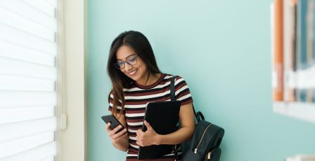 Teacher looking at her mobile phone in a library