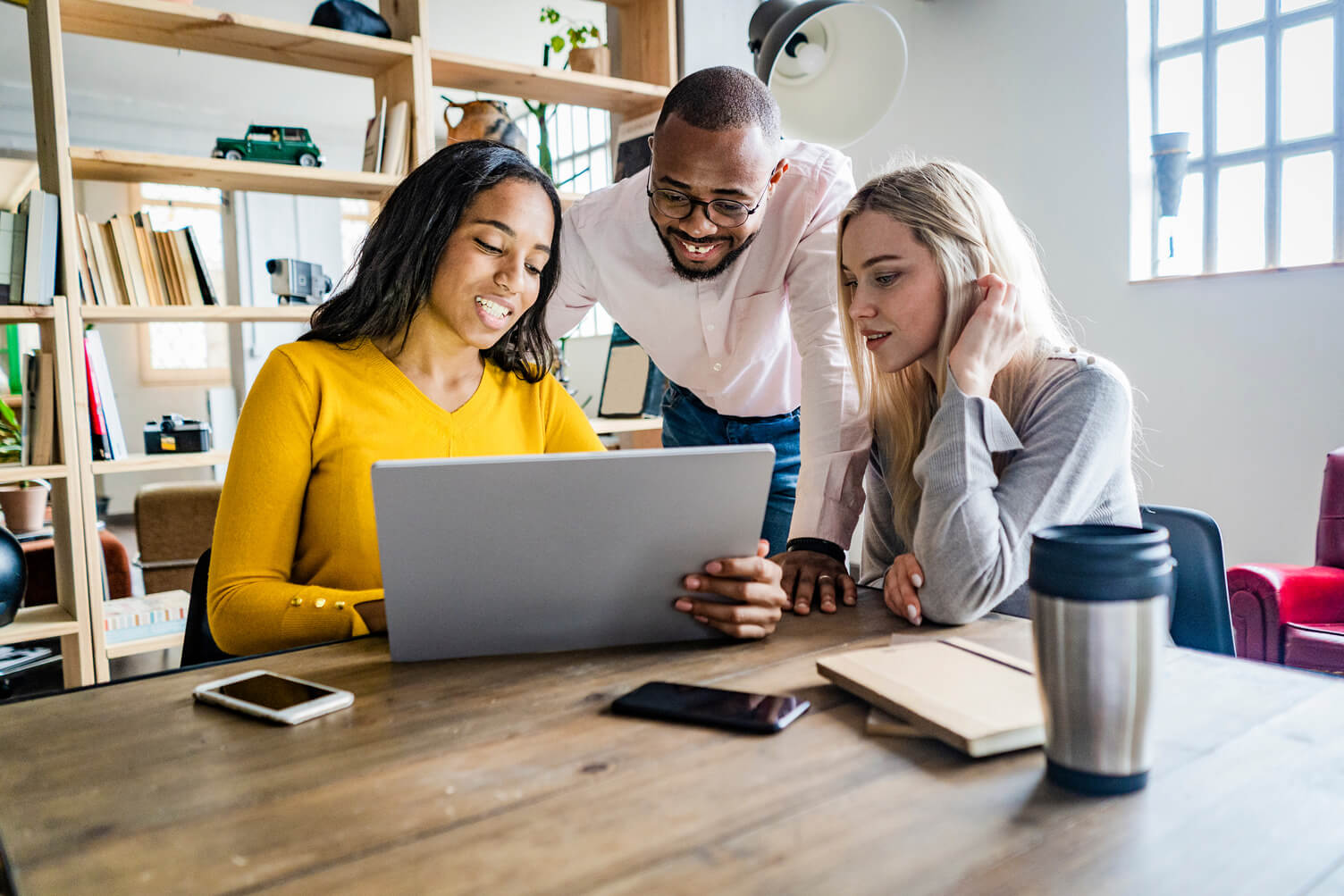 two women and a man looking at a laptop in an office enviroment